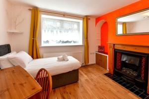 a room with a bed and a fireplace and a table at Host & Stay - Oxford Street House in Swansea