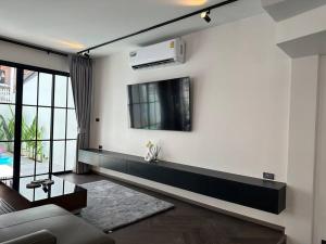 a living room with a couch and a tv on a wall at House 148 Patong Pool Villa 4BR Near Beach in Patong Beach