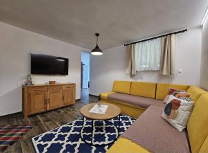 a living room with a yellow couch and a flat screen tv at Chata Partizánka in Liptovský Ján