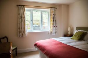 a bedroom with a bed with a red blanket and a window at Applewood in Much Wenlock