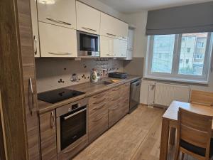 a kitchen with white cabinets and a sink and a table at Apartmány Skalica in Skalica