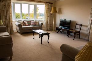 a living room with a couch and a tv and a table at Applewood in Much Wenlock
