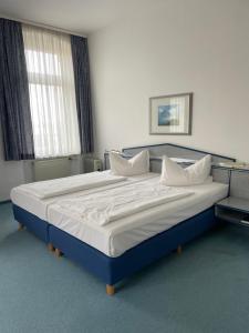 a bedroom with a large bed with white sheets and pillows at Hotel Krone in Arnstadt