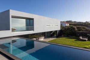 a house with a swimming pool in front of it at White Exclusive Suites & Villas in Lagoa