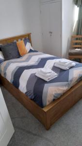 Una cama con marco de madera y toallas encima. en Nice, en Torquay