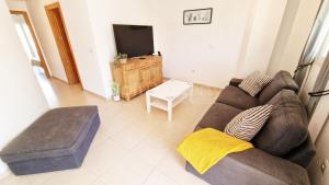 Una sala de estar con un sofá y un televisor. en Delightful Ground Floor 2 bed with access to pool, Wi-Fi, AC, en Sucina