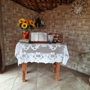 a table with a vase of flowers and books at Hotel Fazenda Recanto in Ouro Branco