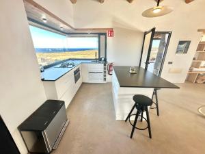 a kitchen with a counter and a table and a stool at Casita Tahona con vistas de infarto al mar y volcanes con absoluta privacidad in Parque Holandes