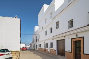un edificio blanco con un coche aparcado en una calle en Piso Ureba, bajo, en Conil de la Frontera