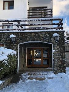 a stone building with a glass door in the snow at Apartur Catedral in San Carlos de Bariloche +122 photos
