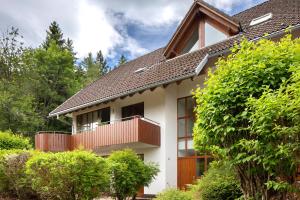 a house with a balcony and trees at Ferienwohnung Am Mehlberg in Hinterzarten