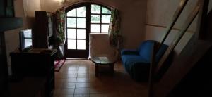 a living room with a blue chair and a window at Maison de village avec jardin in Saint-Louis-et-Parahou