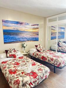ein Hotelzimmer mit zwei Betten und einem Gemälde an der Wand in der Unterkunft Apartamentos COSTA DEL SOL in Benalmádena