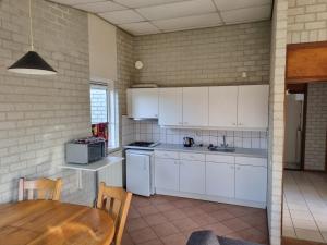 ユリアーナドルプにあるBungalow Noordzee Fの白いキャビネットと木製のテーブルのあるキッチン