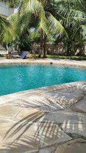 乌昆达Diani Beach Cottage Apartment的一座拥有蓝色海水和棕榈树的游泳池