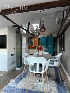 a dining room with a table and white chairs at Пространства за гости Синият час - апартамент Little Wing in Ruse