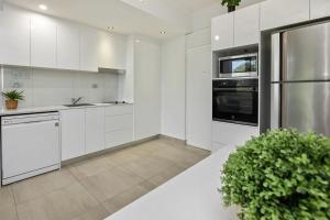 una cucina con armadi bianchi e una pianta in vaso di Seaside Escape - 1BR Hideaway a Fannie Bay