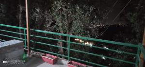 una recinzione verde davanti a un albero di notte di Oak Hill Cottage, in a wooded area valley view near Bakehouse and Chaar Dukaan a Mussoorie 1 altra foto