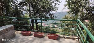 un gruppo di contenitori rossi appoggiati su una ringhiera verde di Oak Hill Cottage, in a wooded area valley view near Bakehouse and Chaar Dukaan a Mussoorie