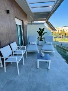 eine Terrasse mit weißen Stühlen und einem blauen Tisch in der Unterkunft Costa Ballena & Eleven Lights in Chipiona