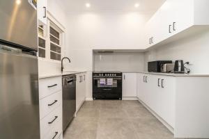 una cucina con armadi bianchi e un apparecchio nero di Beautifully Renovated Inner North Residence - Hosted by CanStay a Canberra