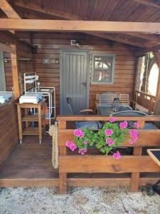 a porch of a cabin with a table and flowers at Chatka Daisy A,B in Pakoštane