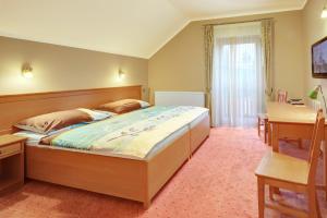 a bedroom with a large bed with a desk and a window at Penzion Harmonie in Žlutice