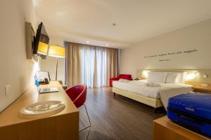 a hotel room with a bed and a desk with a sink at UNAHOTELS Le Terrazze Treviso Hotel & Residence in Villorba