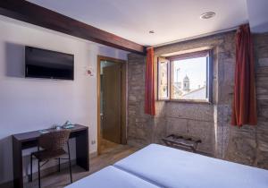 a bedroom with a bed and a desk and a window at Hotel Alda Algalia in Santiago de Compostela