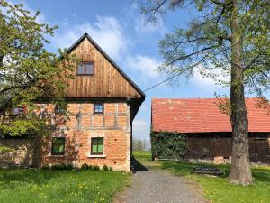 an old brick building with a red roof next to a barn at Grudza83 Bikepoint in Mirsk