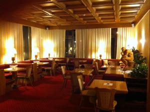 restauracja ze stołami i krzesłami oraz mężczyzna stojący w środku w obiekcie Park Hotel Miramonti w mieście Folgaria