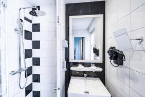 a white bathroom with a sink and a mirror at Hôtel Le Cercle Tour Eiffel in Paris