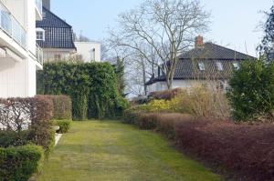 a garden with bushes and trees and a house at Cliff Apartment in Brodten