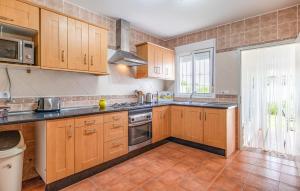 a kitchen with wooden cabinets and a large window at Lovely Home In Chiclana De La Fronter in Chiclana de la Frontera