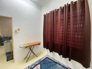 a room with a red curtain and a stool at Homestay Cikgu Ahmed Batu Kikir in Batu Kikir
