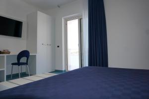 a bedroom with a bed and a chair and a window at Casa del Mare Rooms & Apartments in Marina di Camerota