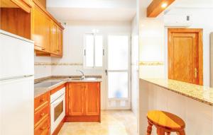 a kitchen with wooden cabinets and a sink and a stool at Amazing Apartment In Torrevieja in Torrevieja