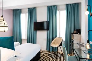 a hotel room with a white bed and green curtains at Hotel Haussmann Saint Augustin in Paris