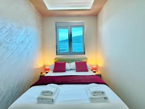 a bedroom with a bed with red pillows and a window at Vila Jadranka Apartments in Herceg-Novi