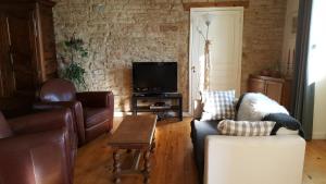 sala de estar con muebles de cuero y TV en Gîte 5 personnes, en Fleurville