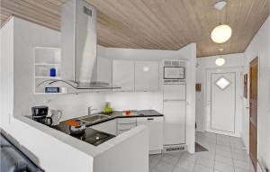 a kitchen with white walls and a wooden ceiling at Holiday Home Romo 22 With Hot Tub in Rømø Kirkeby