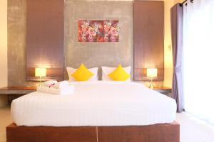 una camera da letto con un grande letto bianco con cuscini gialli di The Meeting House Aonang - self service ad Aonang Beach