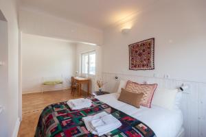 ein Schlafzimmer mit einem weißen Bett mit Handtüchern darauf in der Unterkunft FLH Jacaranda Costa Caparica Beach House in Costa da Caparica