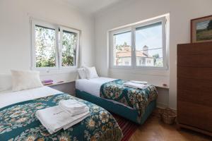 ein Schlafzimmer mit zwei Betten und zwei Fenstern in der Unterkunft FLH Jacaranda Costa Caparica Beach House in Costa da Caparica