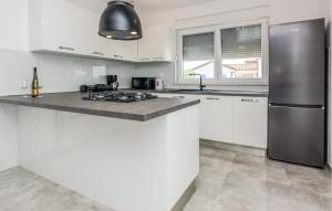 a kitchen with white cabinets and a stainless steel refrigerator at 4 Bedroom Nice Home In Slivnica Donja in Knežević