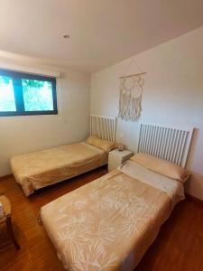 a bedroom with two beds and a window at La Casa de Macarena in Villanueva de la Vera