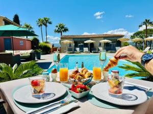 a table with food and drinks and a person eating food at Les Capucines Saint Tropez in Saint-Tropez