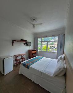 a bedroom with a bed and a table and a window at Dom Pedro Hotel in Petrópolis