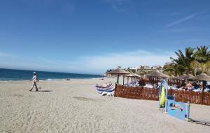 osoba spacerująca po plaży z ludźmi siedzącymi na krzesłach w obiekcie Cozy Home In Nerja With Wifi w mieście Nerja