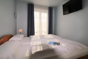 a bedroom with a white bed with a book on it at Villa Rosita Fewo 5 - SANDKÖRNCHEN in Rerik
